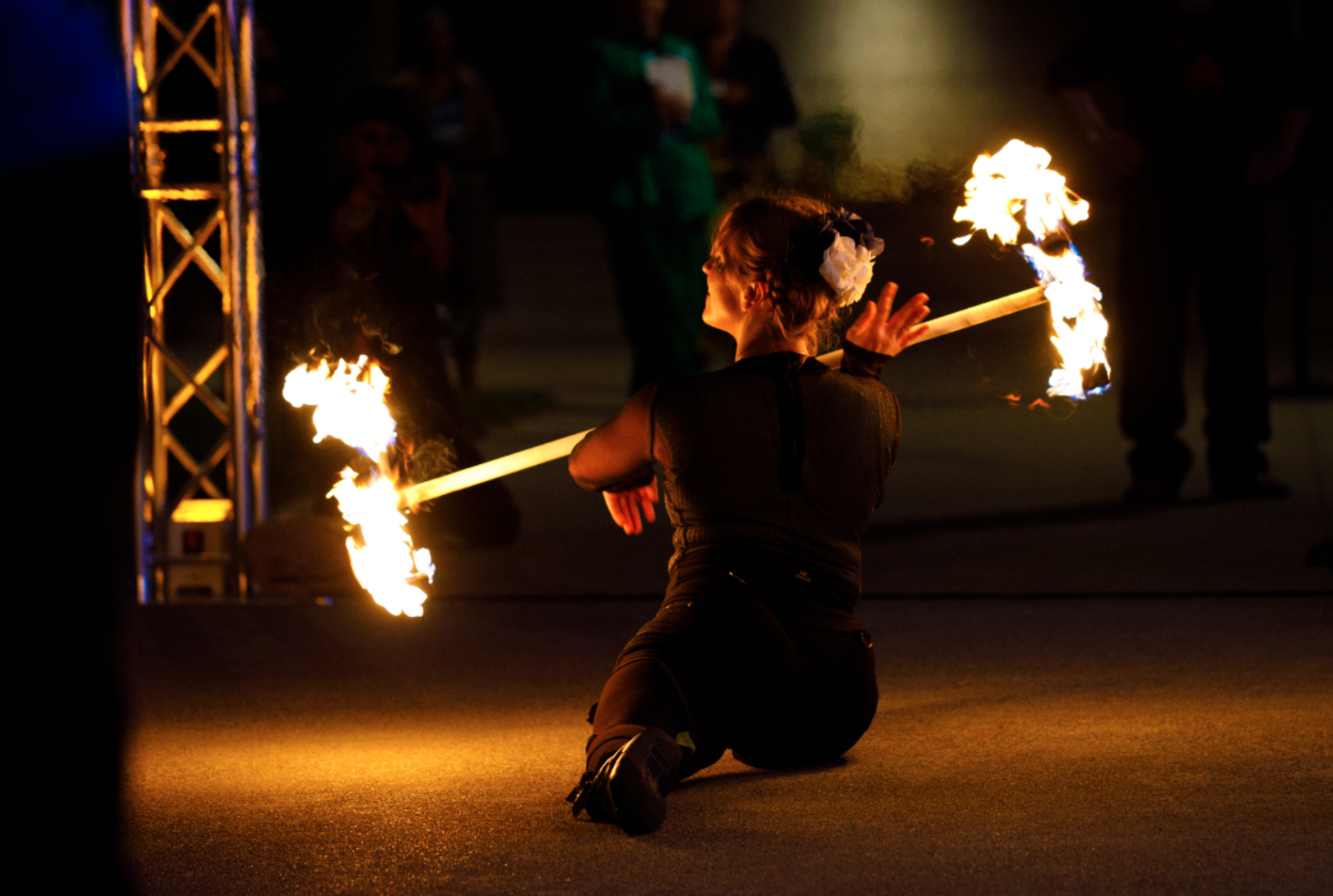 Woman twirling fire while doing the splits
